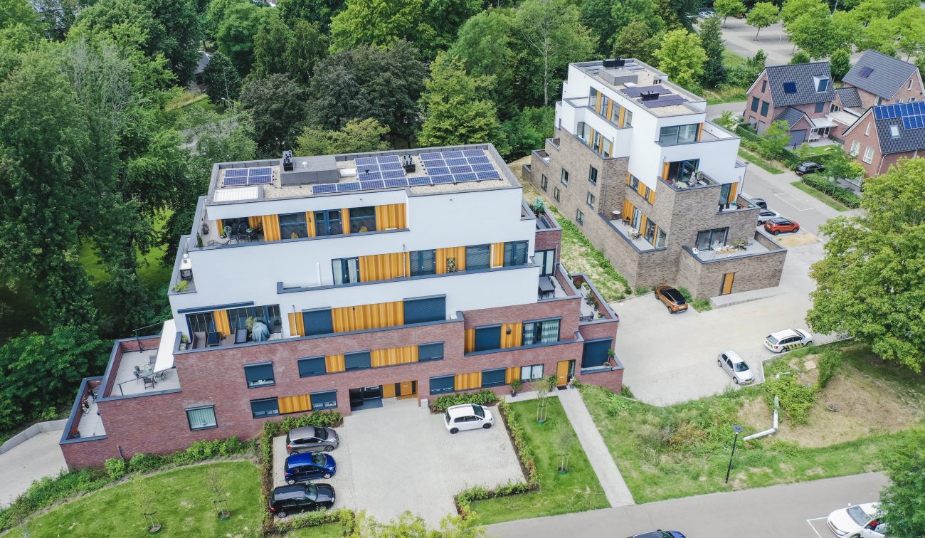 Terrasappartementen in witte stuclaag en baksteen met dakterrassen, tussen groen en woonwijk — Gebiedsontwikkeling Parkheuvel Heerlen