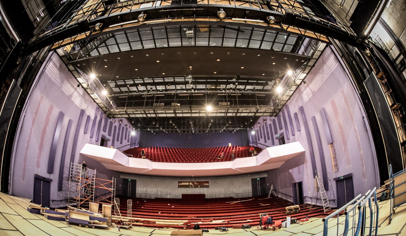 Verbouwing grote zaal Vrijthof: zicht vanaf toneel, steigers, losse stoelen en open technische kap