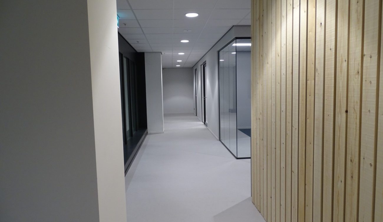 Moderne corridor met witte vloer, downlights en transparante kantoorunits in Hoog Catharijne