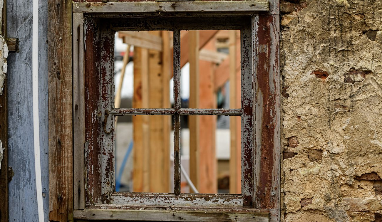 Detail renovatie Naardermeer: verweerd houten raamkozijn met afbladderende verf en nieuwe houtconstructie
