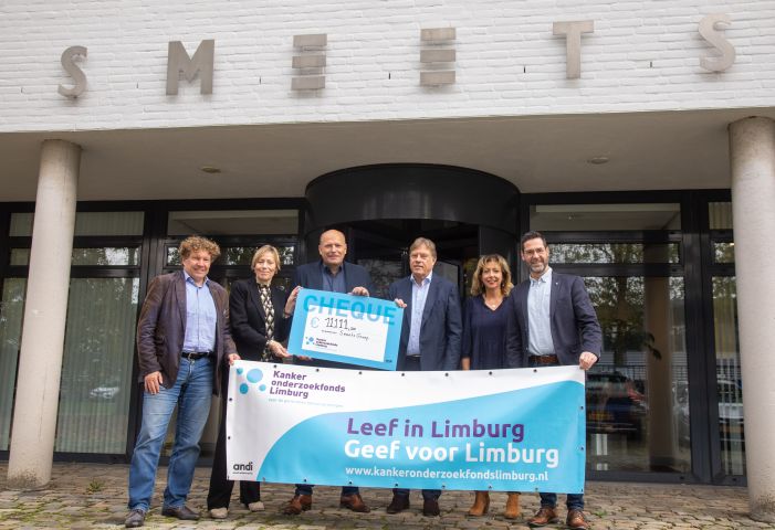 Vijf mensen houden een doek en een cheque vast