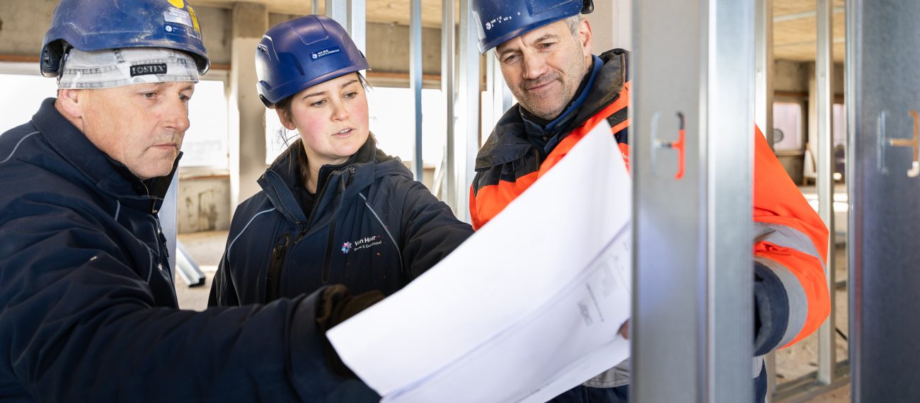 drie werknemers van Van Heur kijken naar een tekening op de bouwplaats