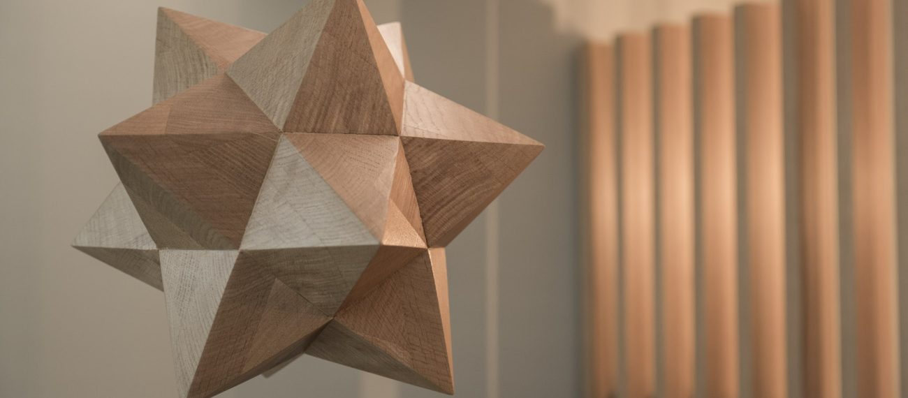Houten geometrisch object met veelvlakkige punten in een interieur.