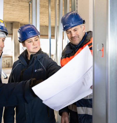 drie werknemers van Van Heur kijken naar een tekening op de bouwplaats