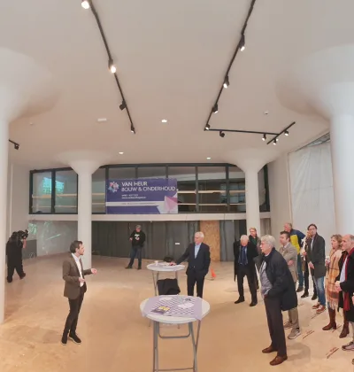 Bijeenkomst met bezoekers en statafels in lichte zaal met grote witte kolommen