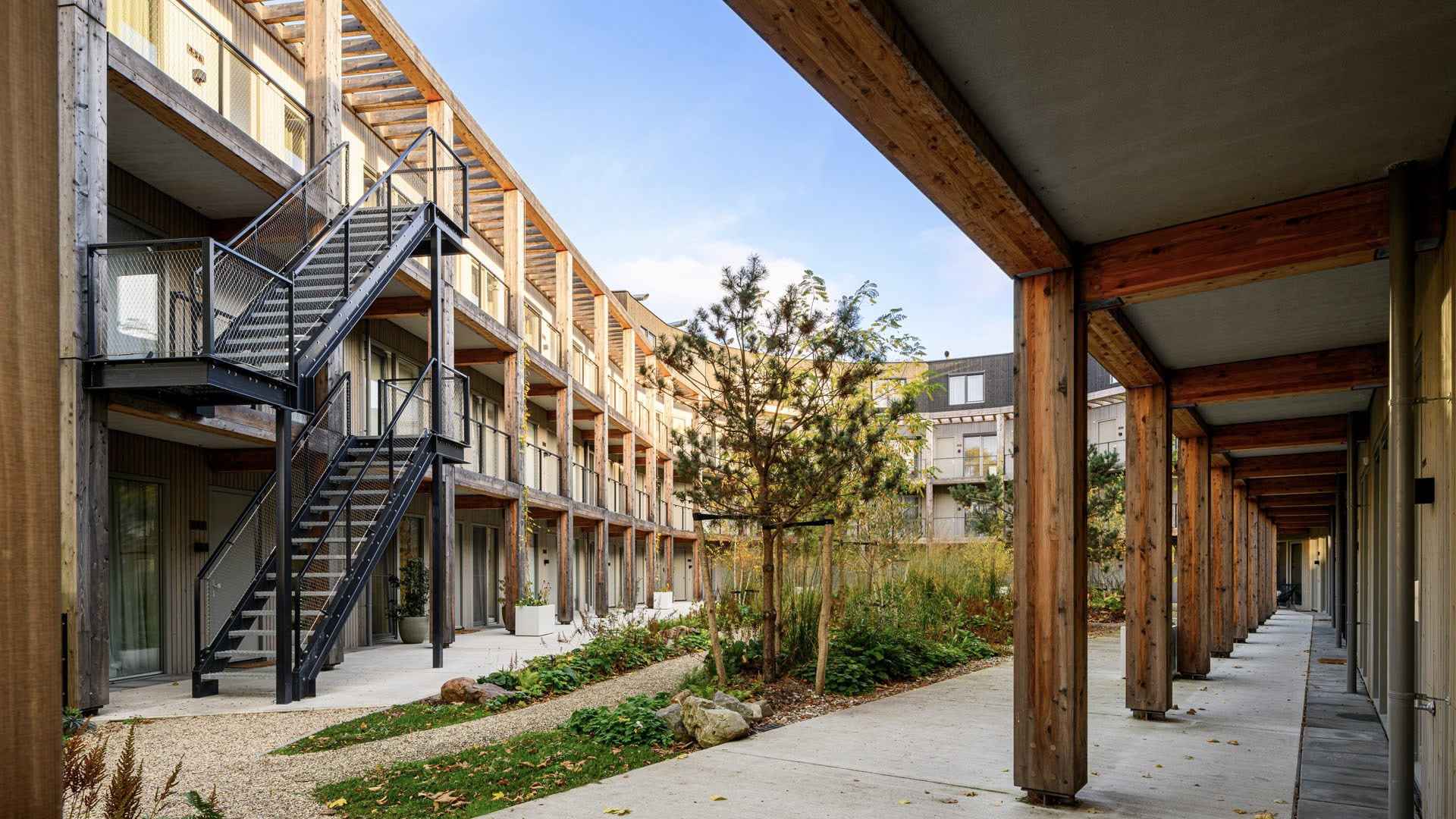 Nieuwbouw ROOT Eindhoven – duurzaam binnenhof met houten constructies, galerijen en groene natuurinclusieve tuin.