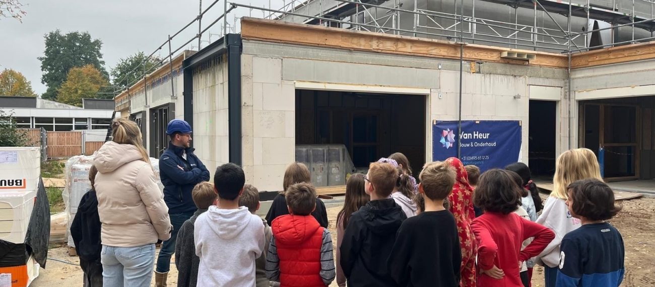 Groepje scholieren staan op ene bouwplaats naar een uitleg te luisteren