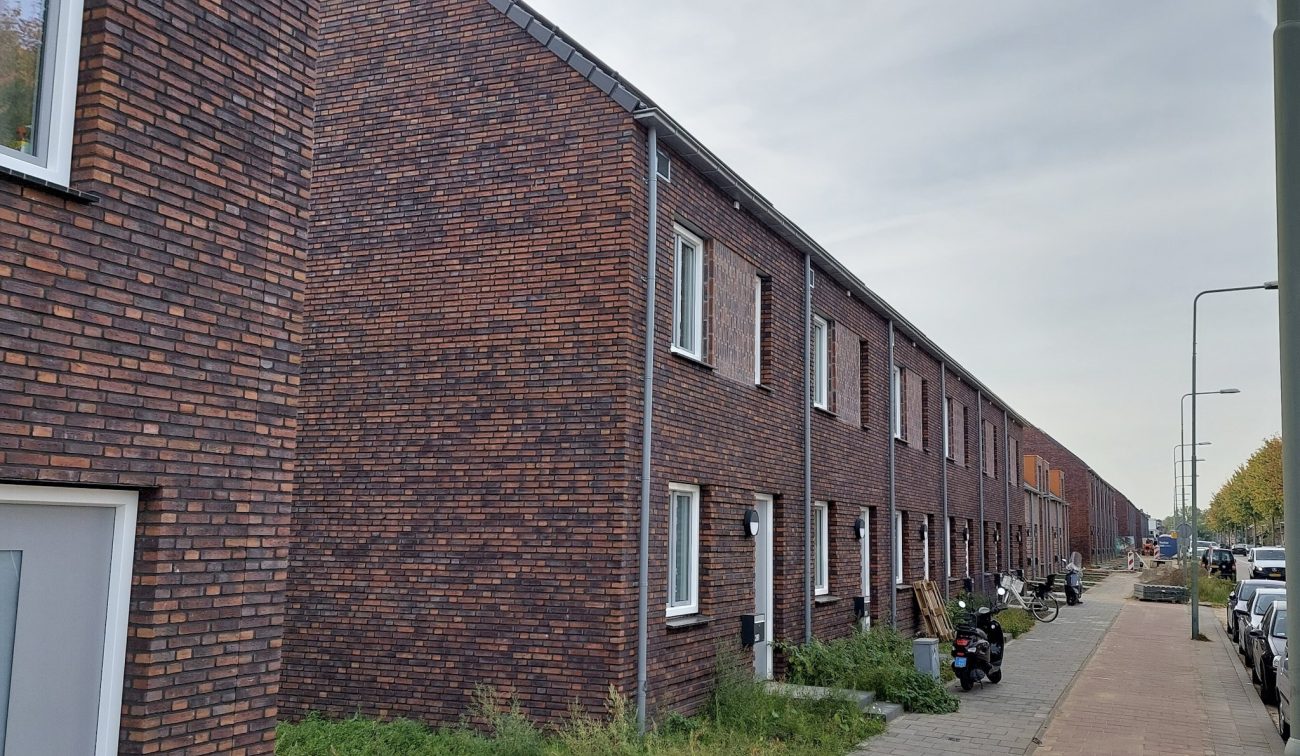 Nieuwbouw Bredeweg Roermond – lange rij bakstenen eengezinswoningen met witte kozijnen, stoep met lantaarnpalen