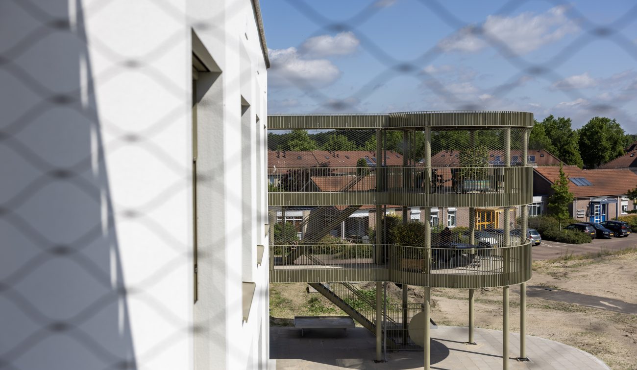 Detail zorgwoningen Horst: cilindrische galerij met metalen lamellen en trappartij.