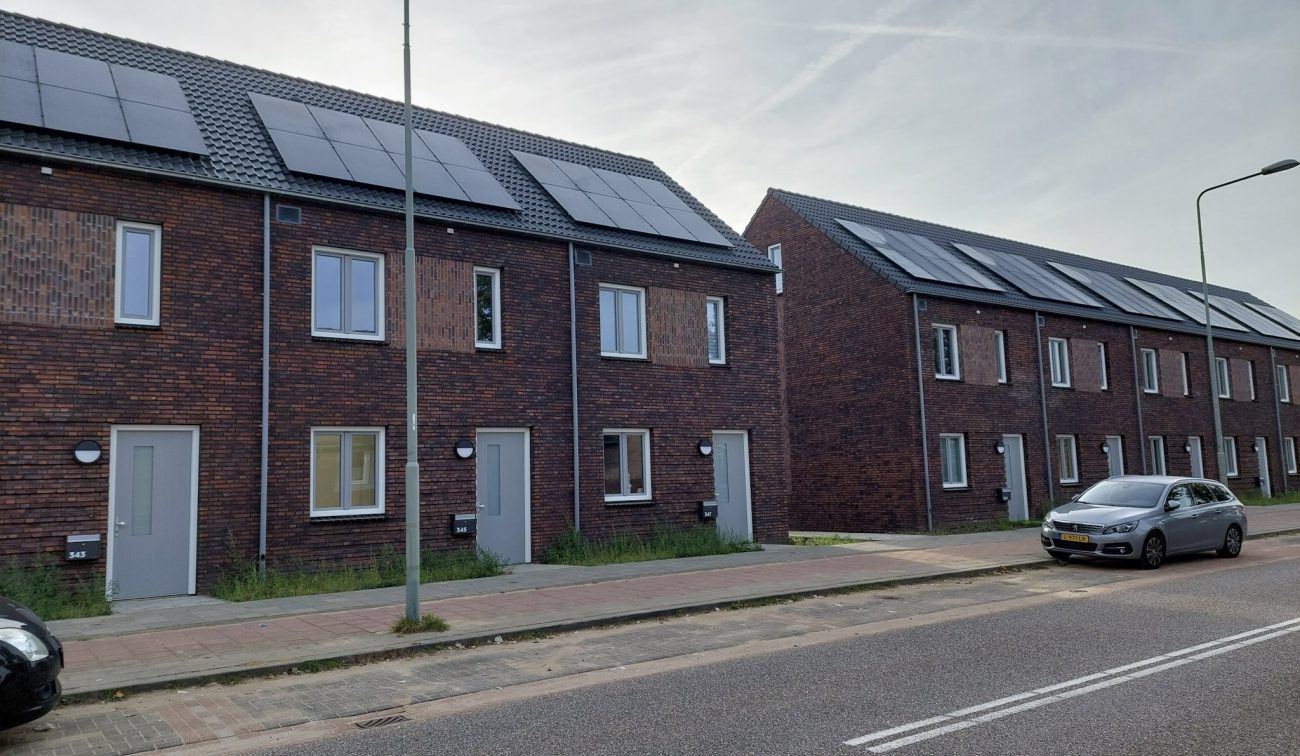 Nieuwbouw Bredeweg Roermond – rijwoningen in donker baksteen met grijze kozijnen en zonnepanelen op zadeldak, straat met lantaarnpalen en auto
