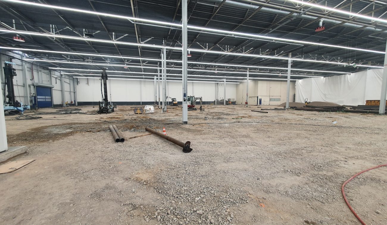 Renovatie van de betonvloer in hal A50 bij DAF Eindhoven, met opengebroken vloer, bouwmaterieel en voorbereidende werkzaamheden in de fabriekshal.