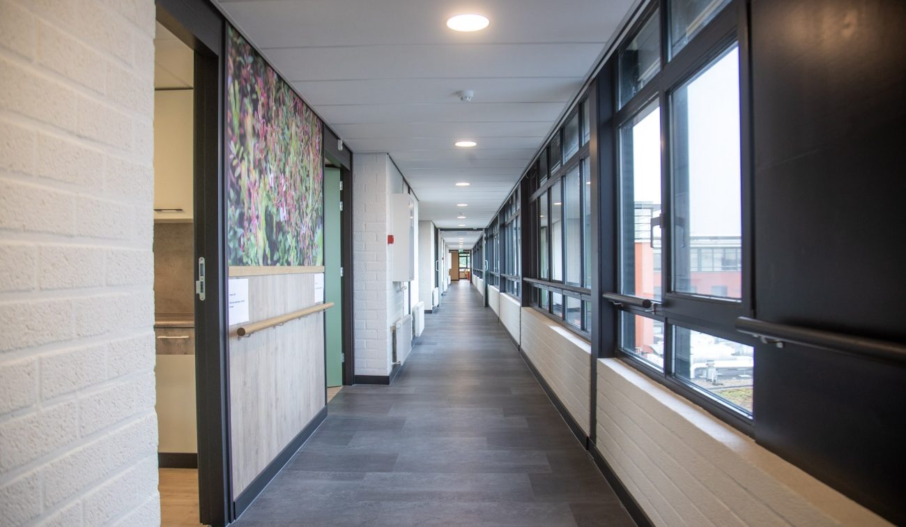 Verzorgingshuis Aan de Bleek: lichte gang met grote ramen, handgrepen en onderhoudsvriendelijke vloer