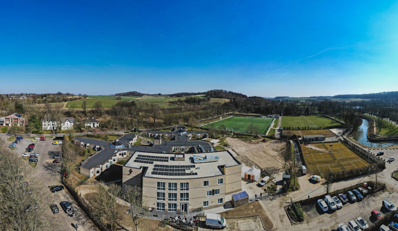Zorgcomplex Valkenheim vanuit de lucht, parkeerplaatsen en groen valleilandschap.