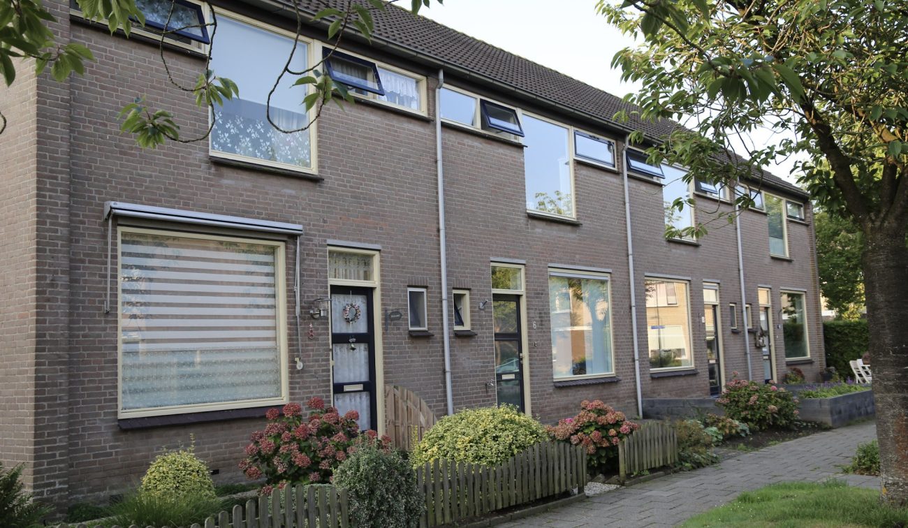 Bloemenwijk Almkerk: rijwoningen in baksteen met grote ramen, luifels, voortuinen en bomen in straat