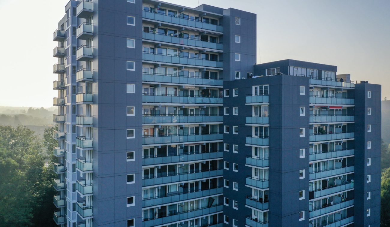 Close-up van de gerenoveerde Aambosveldflat in Heerlen, met donkergrijze gevel en rijen glazen balkons, gefotografeerd in zacht ochtendlicht.