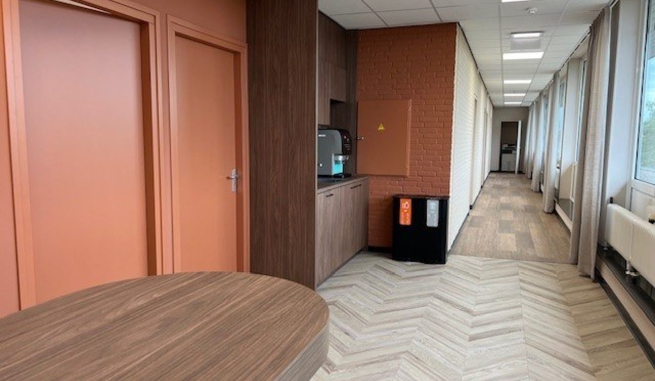 Renovatie Schuttershof Brunssum – koffiecorner aan gang met visgraatvloer, oranje deuren en veel daglicht