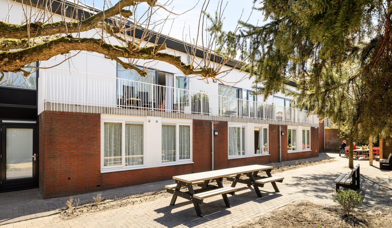 Renovatie en optopping Plataanlaan Baarn: woongebouw met balkonhekken, baksteen, tuin en oude bomen.