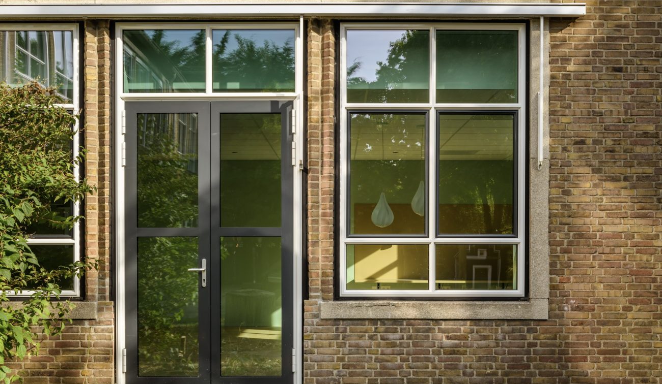 Renovatie OBS De Fakkel Utrecht: stalen deurpartij met bovenlicht, roedeverdeling en bakstenen gevel