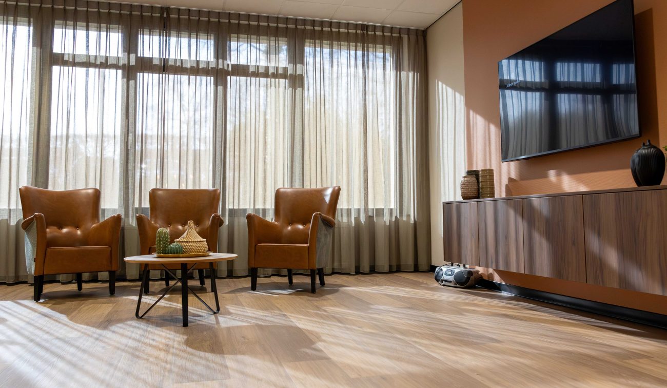 Een woonkamer met drie stoelen een tafeltje en een tv