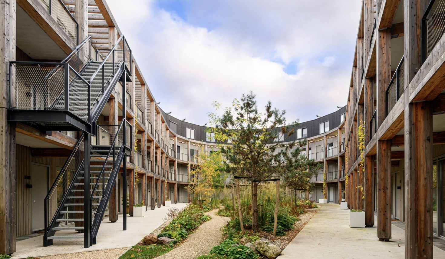Nieuwbouw ROOT Eindhoven – duurzaam binnenhof met houten gevels, galerijen en groene natuurinclusieve tuin.