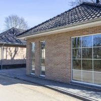 Moderne bakstenen woningen met grote ramen en pannendaken langs een rustige straat.