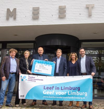 Vijf mensen houden een doek en een cheque vast