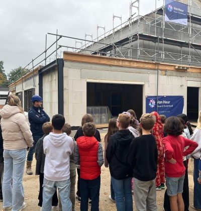 Groepje scholieren staan op ene bouwplaats naar een uitleg te luisteren