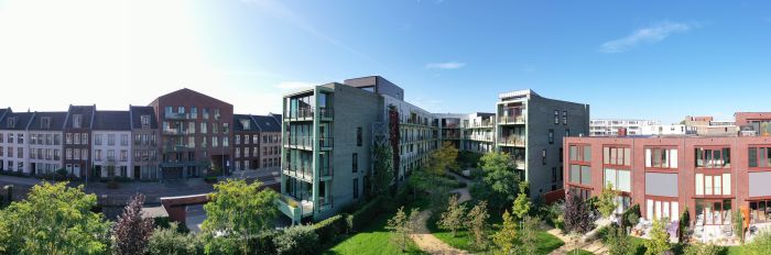 CPO Sphinx Maastricht – panorama van binnenhof met groene tuin, paden en moderne woonblokken in baksteen en groen beton