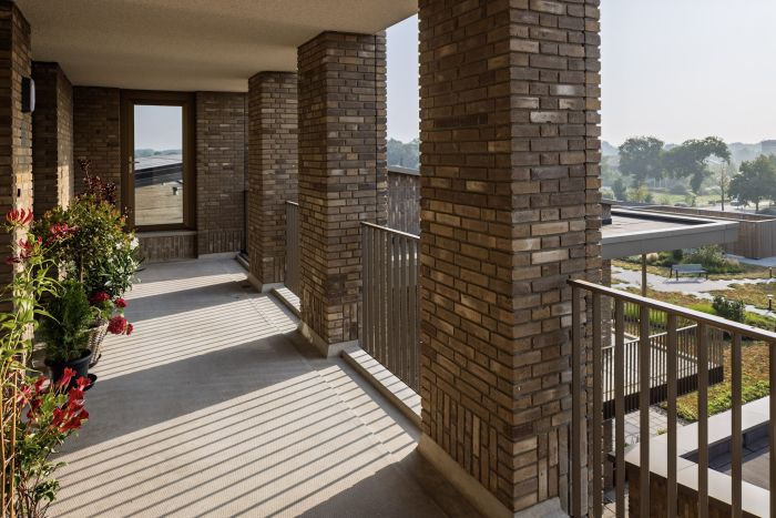 De Scheperij Teteringen: galerij met bakstenen kolommen, plantenbakken en zicht op groene binnentuin