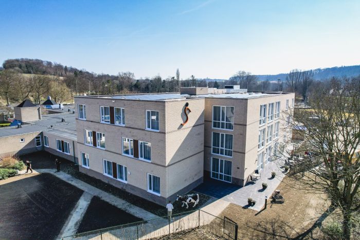Zorgcomplex Valkenburg, moderne blok met lichte baksteen, paden en terrassen aan gevel.