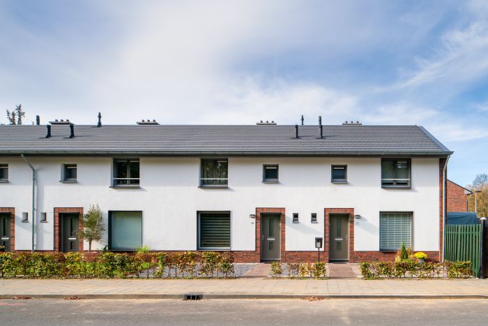 Rij eengezinswoningen met witte gevel en baksteenaccenten, grijs pannendak en kleine voortuinen langs de stoep in wijk Nazareth (Maastricht).