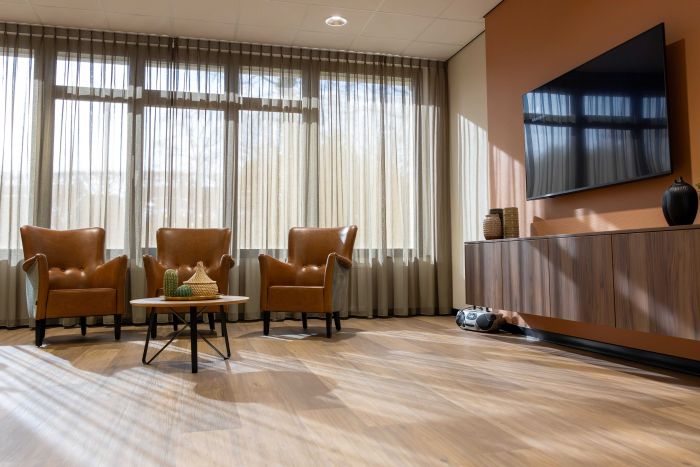 Een woonkamer met drie stoelen een tafeltje en een tv