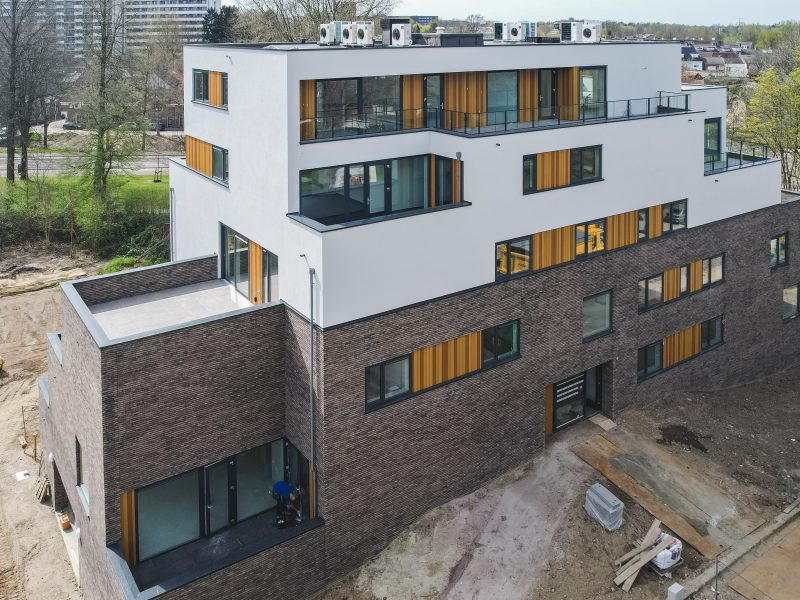 Modern woongebouw met dakterrassen, verticale houten accenten en glas aan bosrand — Gebiedsontwikkeling Parkheuvel Heerlen