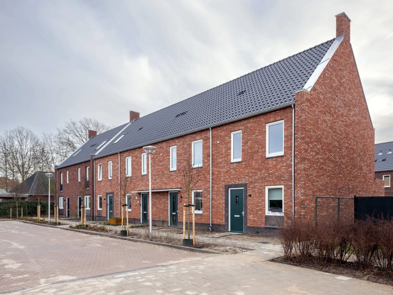 Rijwoningen met bakstenen gevels en dakkapellen langs rustige straat in nieuwbouwwijk